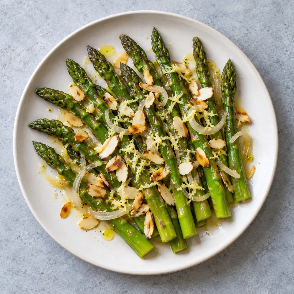 Asperges au gingembre et aux amandes : asperges vertes, oignon, gingembre et amandes sur assiette blanche.