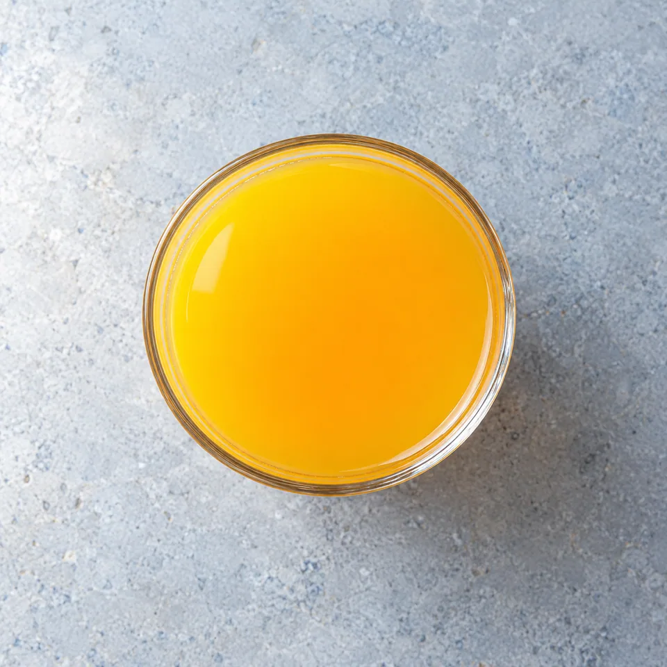 Un grand verre de jus d'orange au miel, liquide orange vif et limpide.