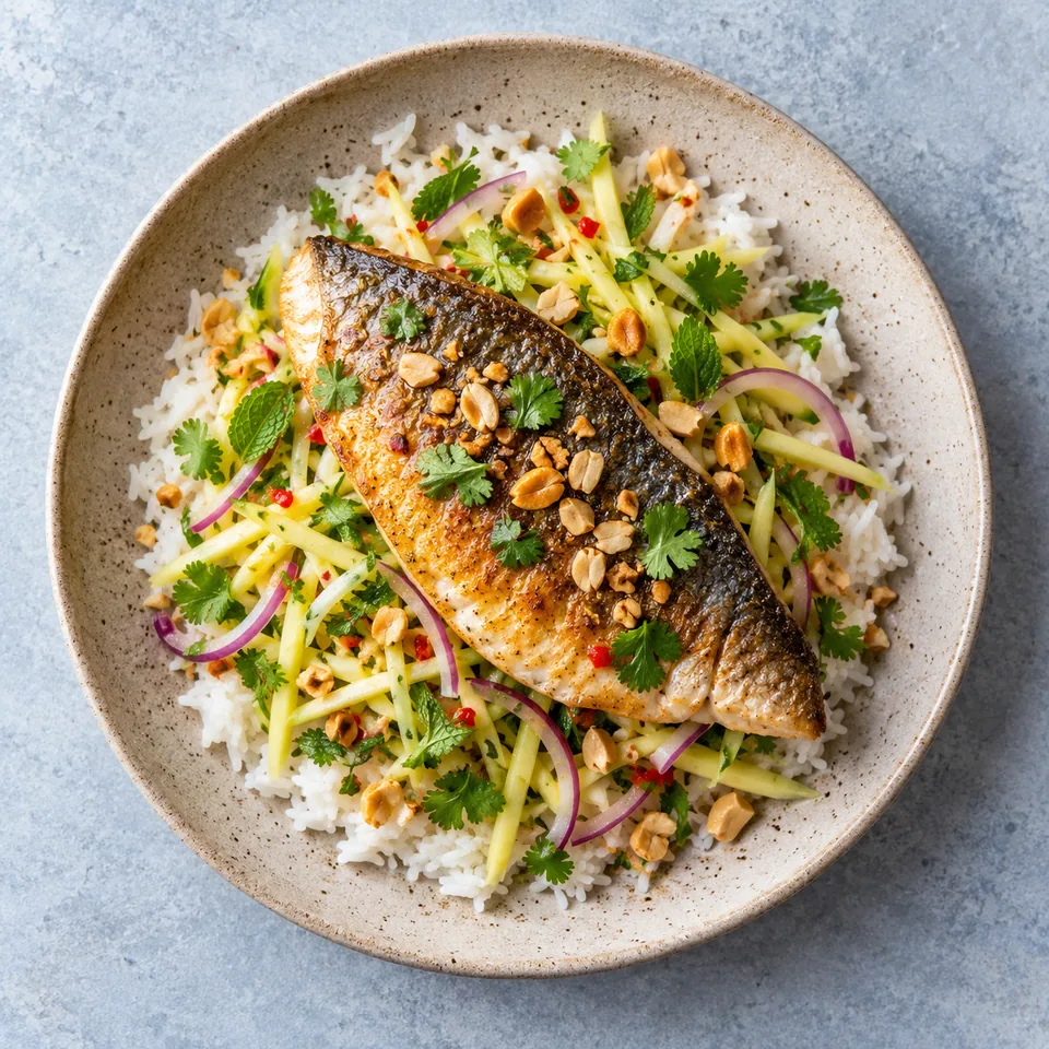 Dorade poêlée avec peau croustillante sur riz jasmin et salade de mangue verte thaïe, parsemée de cacahuètes.