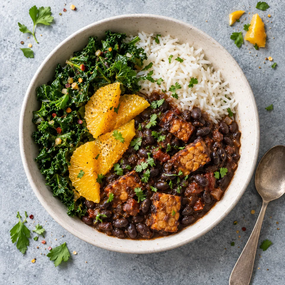 Feijoada de haricots noirs au tempeh et riz dans un bol blanc cassé, garnie de quartiers d'orange et de kale vert.