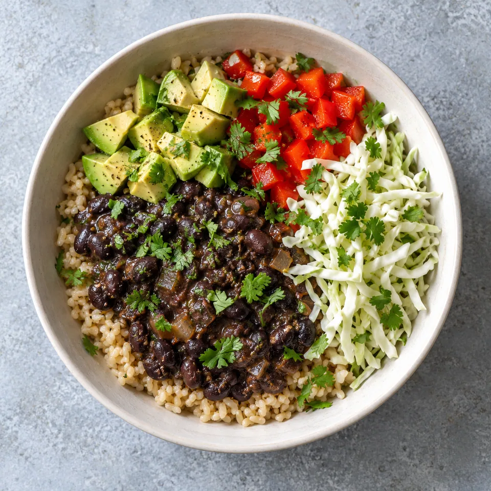 Bol de riz complet, haricots noirs mijotés, dés d'avocat, poivron rouge et chou croquant, parsemé de coriandre.