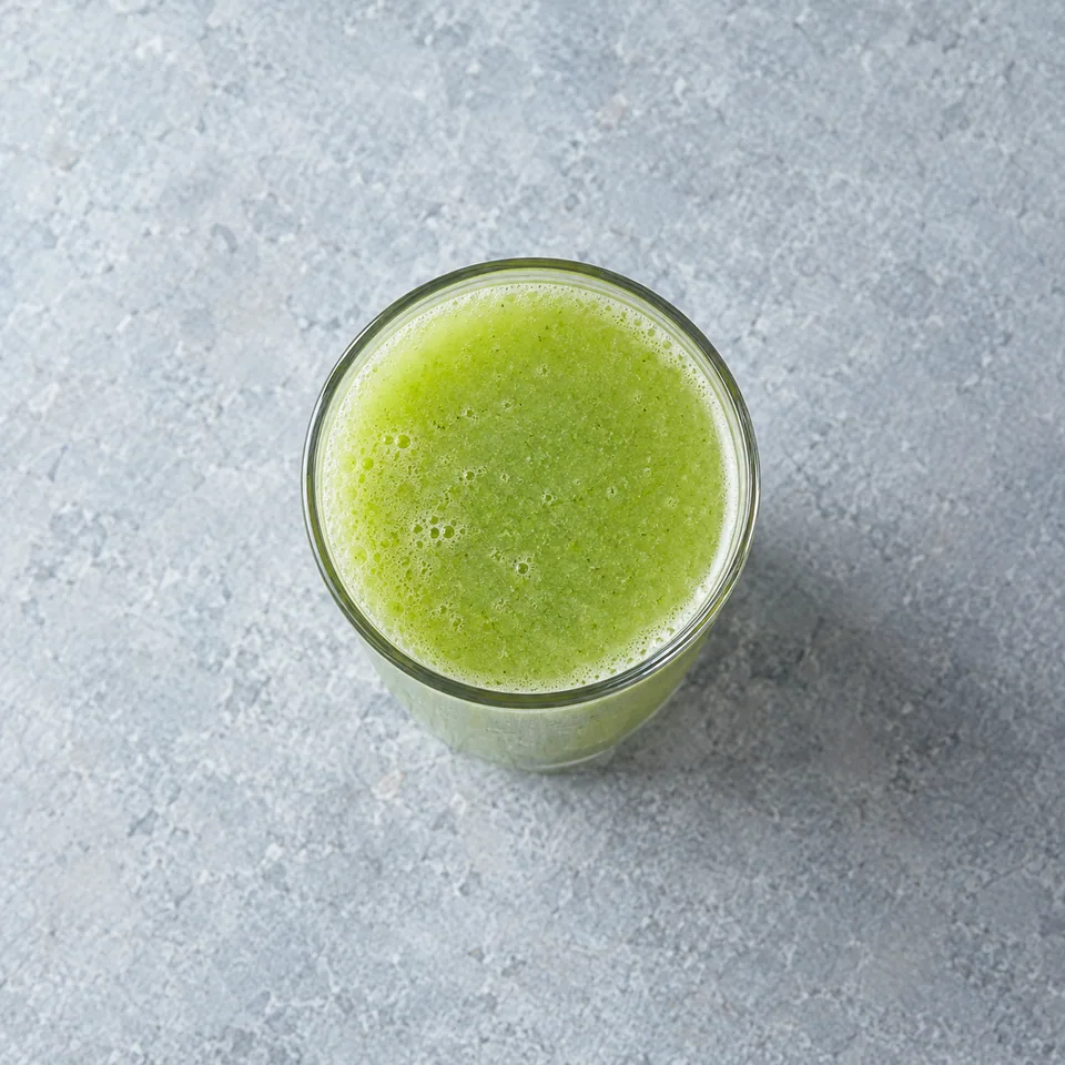 Jus de concombre, pomme et céleri vert pâle dans un verre haut