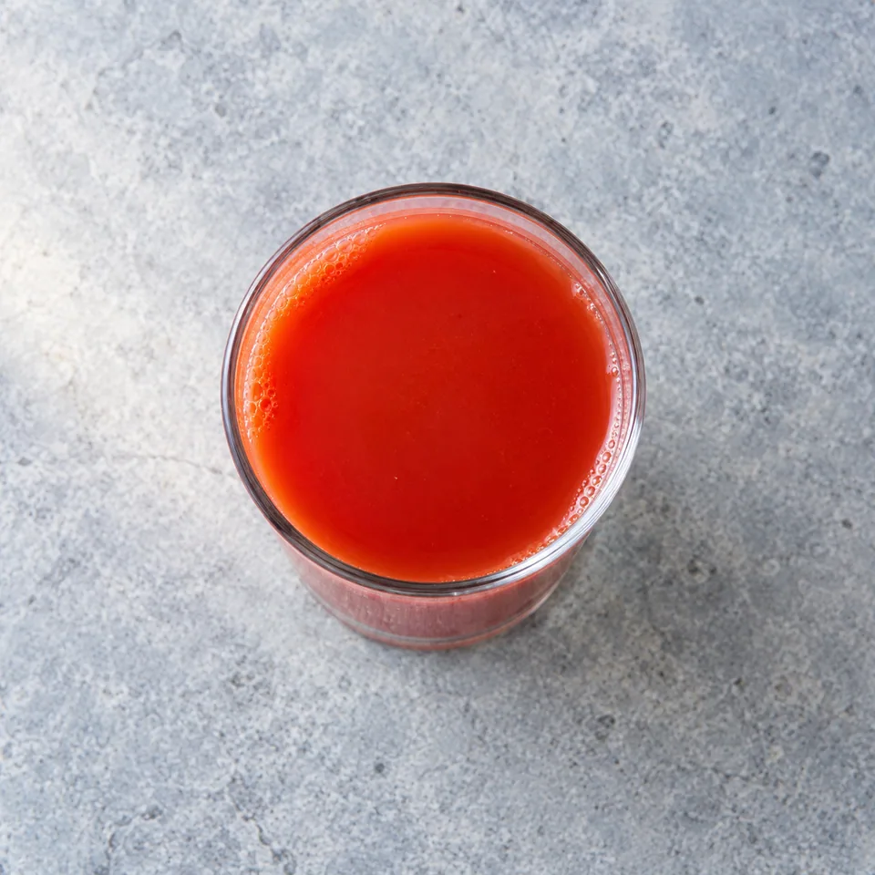 Un verre de jus de tomates maison rouge vif et homogène, servi frais.