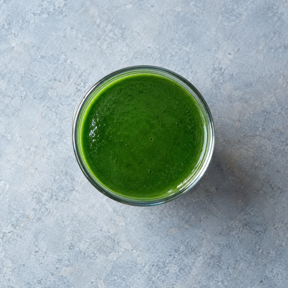 Jus vert à la spiruline servi dans deux verres hauts, de couleur vert émeraude uniforme et lisse.