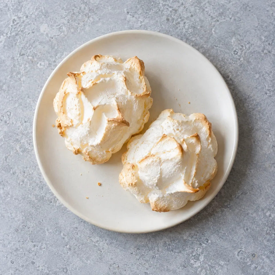 Meringues minute au micro-ondes : deux meringues blanches et croustillantes sur une assiette blanche.