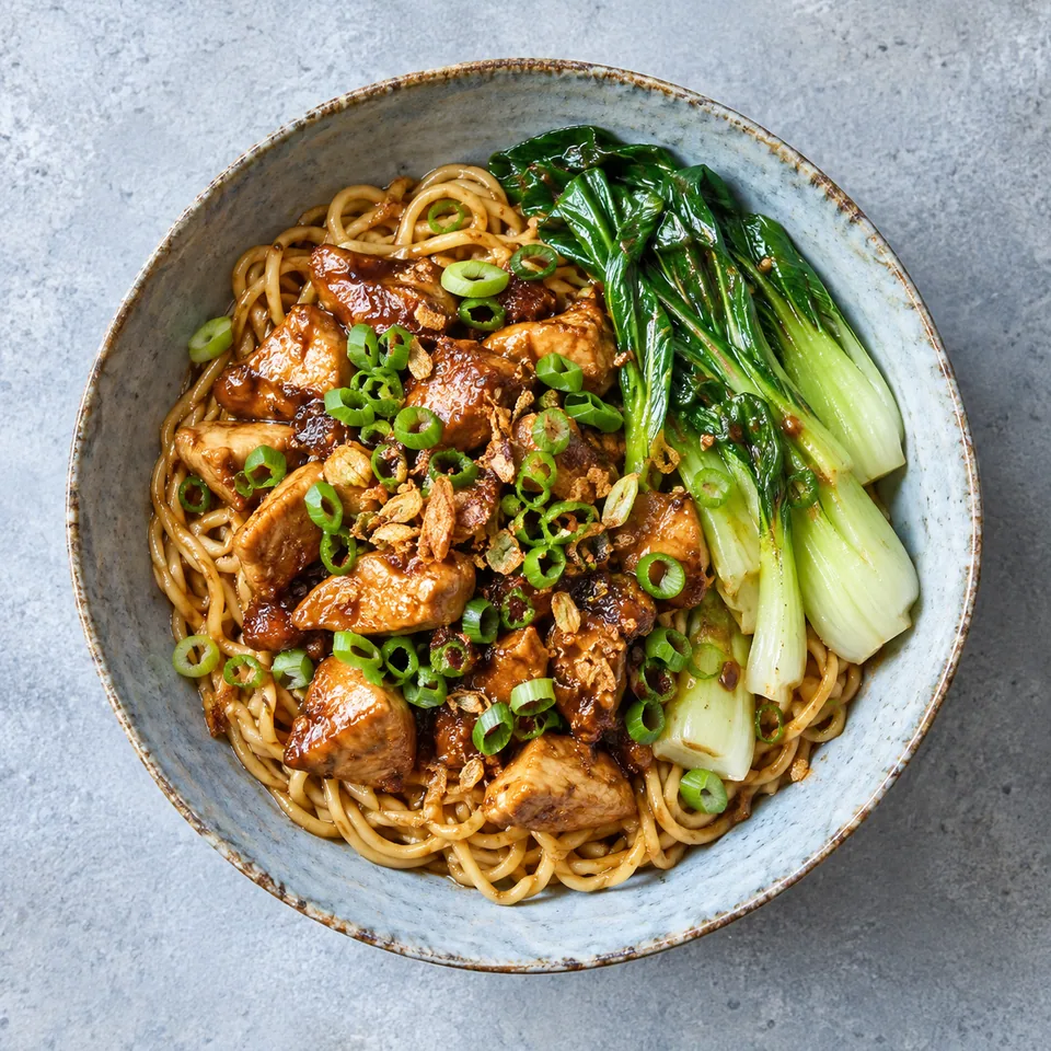 Mie ayam : nouilles, poulet dés et pak choï dans un bol bleu-gris, garni de ciboule.