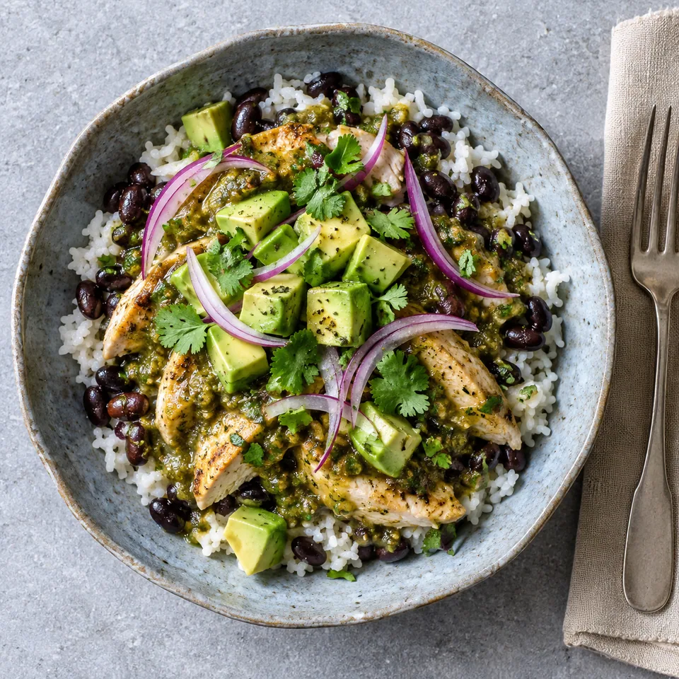 Bol de poulet en salsa verte sur riz et haricots noirs, garni d'avocat et coriandre.