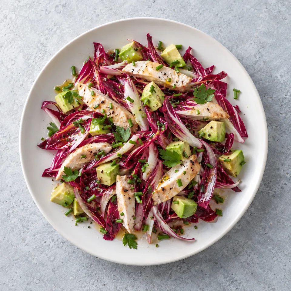 Salade d’endives rouges au poulet et avocat : lamelles de poulet, dés d'avocat et endives rouges ciselées, garnies d'herbes fraîches.