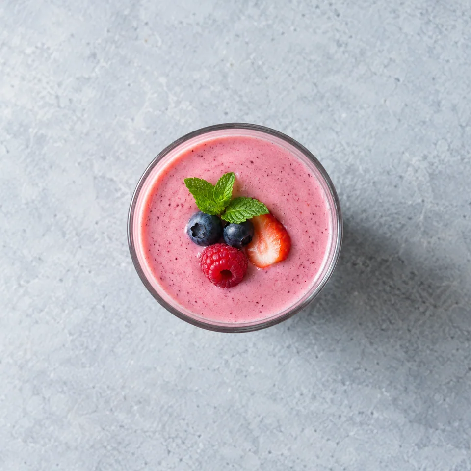 Smoothie rose aux fruits rouges servi dans deux verres hauts, texture lisse et homogène.
