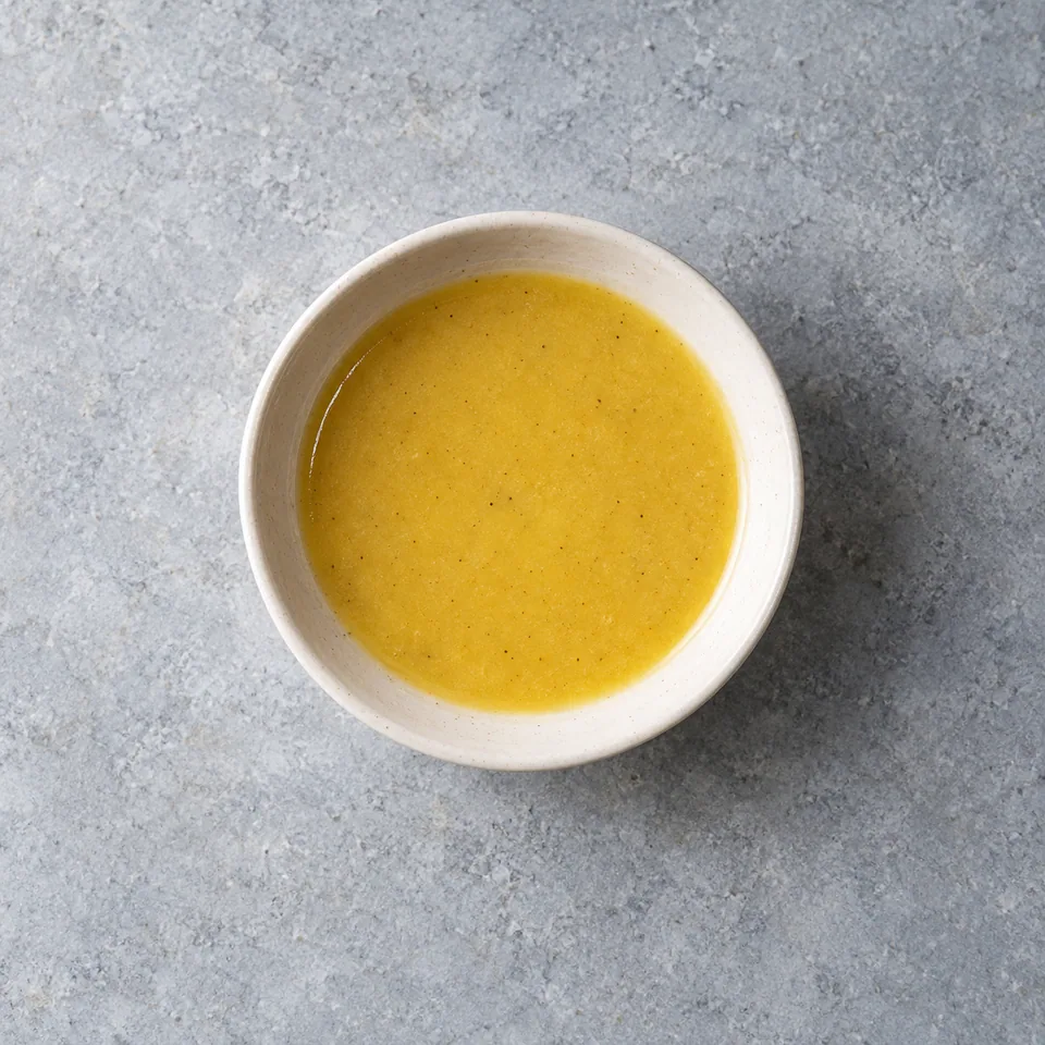 Vinaigrette pomme-cidre jaune doré, lisse et crémeuse, servie en petite portion dans un bol.